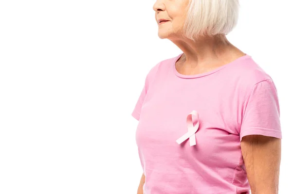 Vista recortada de la cinta rosa de la conciencia del cáncer de mama en la camiseta en la mujer mayor aislado en blanco - foto de stock