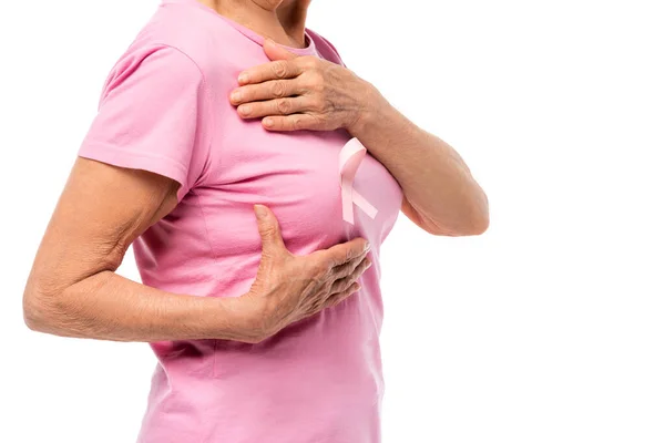 Vista recortada de la mujer anciana en camiseta rosa con cinta de conciencia de cáncer de mama aislado en blanco - foto de stock