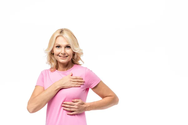 Mujer rubia mirando a la cámara mientras toca el pecho aislado en blanco, concepto de cáncer de mama - foto de stock