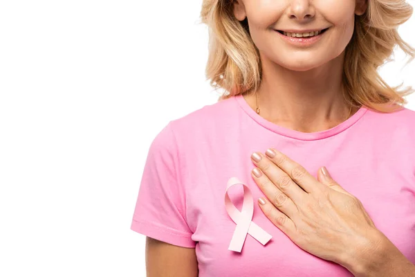 Vue recadrée de la femme blonde avec la main sur la poitrine avec ruban de sensibilisation au cancer du sein sur t-shirt isolé sur blanc — Photo de stock