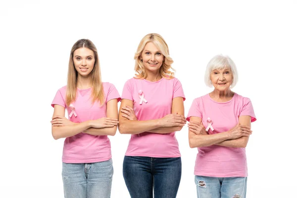 Mujeres con cintas rosadas de conciencia sobre el cáncer de mama y brazos cruzados mirando a la cámara aislada en blanco - foto de stock