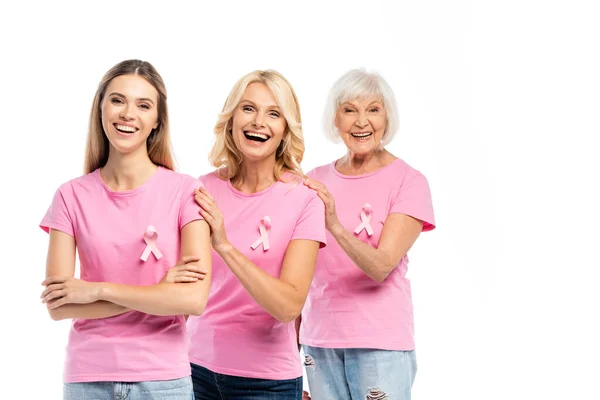 Excited women with pink ribbons of breast cancer awareness hugging isolated on white — Stock Photo