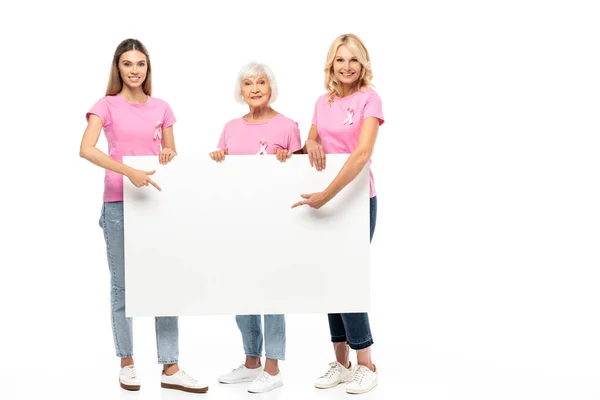 Femmes avec des rubans de sensibilisation au cancer du sein pointant vers le tableau vide sur fond blanc — Photo de stock