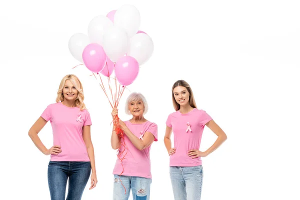 Donne in t-shirt rosa con nastri e palloncini guardando la fotocamera isolata su bianco — Foto stock