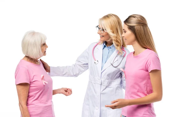 Доктор со стетоскопом смотрит на женщину с розовой лентой и футболкой, изолированной на белом — стоковое фото