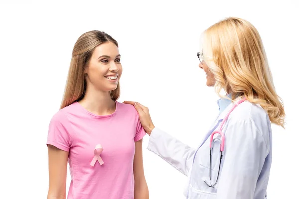 Médecin câlin jeune femme avec ruban de sensibilisation au cancer du sein sur t-shirt isolé sur blanc — Photo de stock