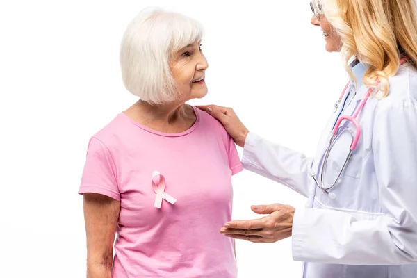 Doctor embracing senior woman with pink ribbon of breast cancer awareness isolated on white — Stock Photo