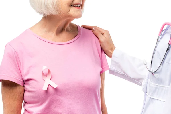 Vista ritagliata del medico che abbraccia la donna anziana con nastro rosa sulla t-shirt isolata sul bianco — Foto stock