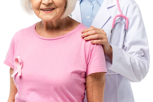 Vista recortada del médico con estetoscopio abrazando a una anciana con cinta rosa aislada en blanco - foto de stock
