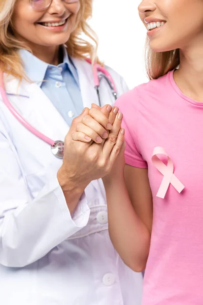 Cropped view of doctor holding hand of young woman with pink ribbon on t-shirt isolated on white — Stock Photo