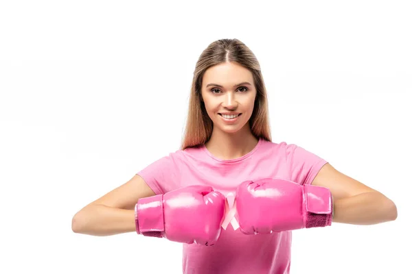 Mujer con guantes de boxeo rosa mirando a la cámara mientras sostiene cinta de conciencia de cáncer de mama aislado en blanco - foto de stock