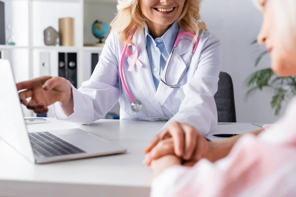 Enfoque selectivo del médico con cinta rosa que reconforta al paciente en el lugar de trabajo - foto de stock