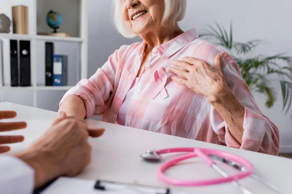 Ausgeschnittene Ansicht einer älteren Frau mit Hand in der Nähe eines rosafarbenen Bandes in der Nähe eines Arztes — Stockfoto