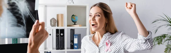 Panoramaaufnahme einer jungen erwachsenen Frau mit Ja-Geste in der Nähe von Arzt mit Röntgenbild — Stockfoto