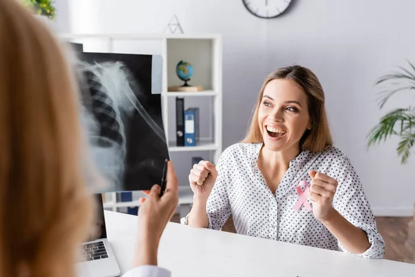 Selektiver Fokus einer jungen erwachsenen Frau mit Yeah-Geste in der Nähe eines Arztes mit Röntgenbild — Stockfoto