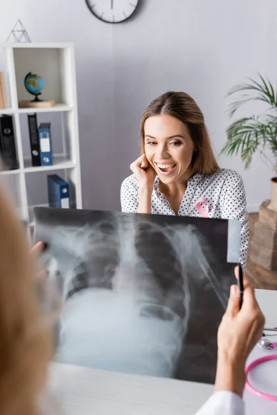 Selective focus of young adult woman sitting in front of doctor with chest x-ray — Stock Photo