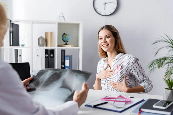 Concentration sélective du patient avec les mains sur le sein assis près du médecin avec radiographie — Photo de stock