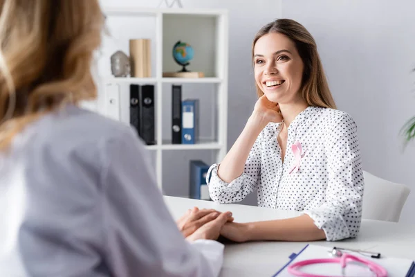 Enfoque selectivo de la mujer joven adulta sentada y cogida de la mano con el médico - foto de stock