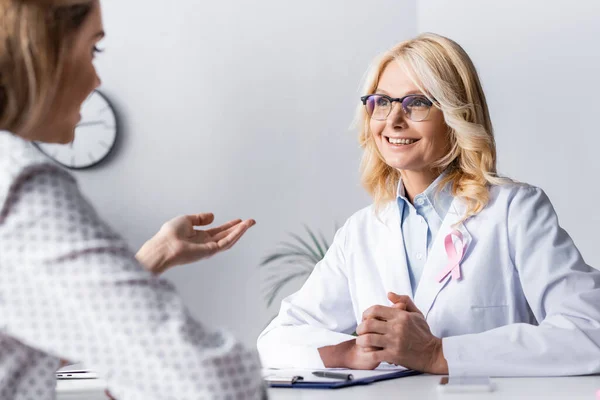Selective focus of doctor with clenched hands sitting near patient at workplace — Stock Photo