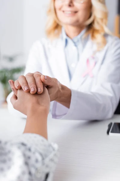 Enfoque selectivo del paciente cogido de la mano con el médico de bata blanca - foto de stock