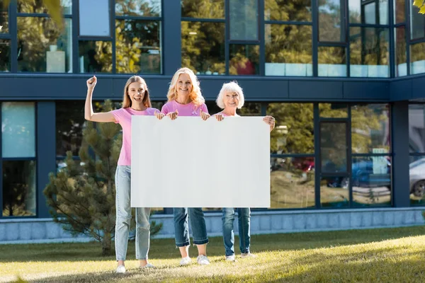 Jeune femme adulte avec geste oui debout près des femmes avec une pancarte vierge à l'extérieur — Photo de stock