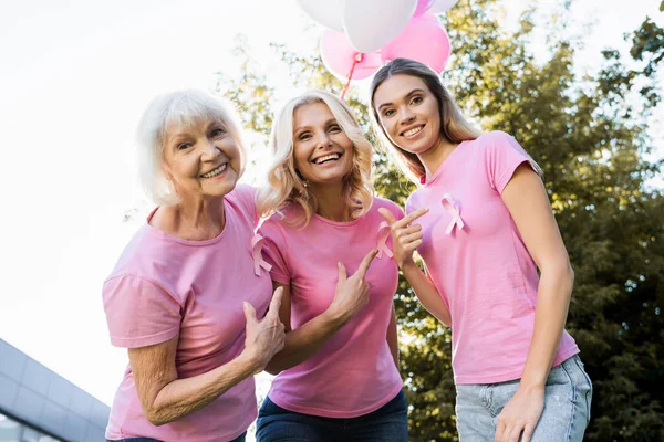 Frauen zeigen mit dem Finger auf Brustkrebsbänder im Freien — Stockfoto