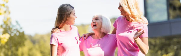 Foto panorámica de tres mujeres abrazándose y riendo, concepto de cáncer de mama - foto de stock