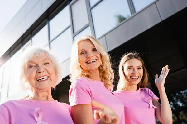 Donne con segni di consapevolezza del cancro al seno abbracciare e guardare la fotocamera — Foto stock