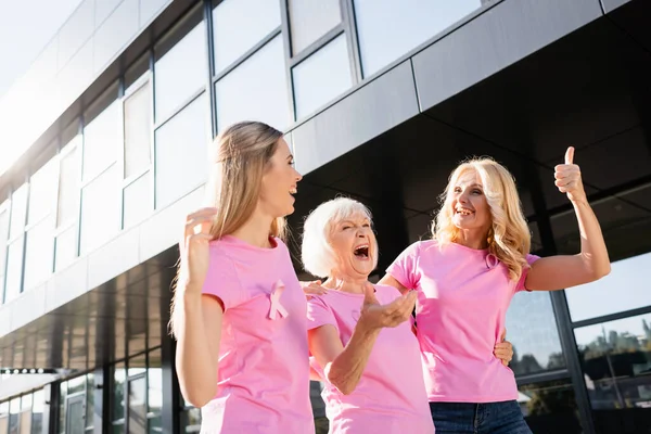 Tres mujeres abrazando y riendo al aire libre, concepto de cáncer de mama - foto de stock