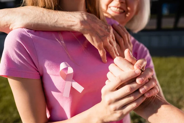 Enfoque selectivo de las mujeres que abrazan y toman la mano al aire libre - foto de stock