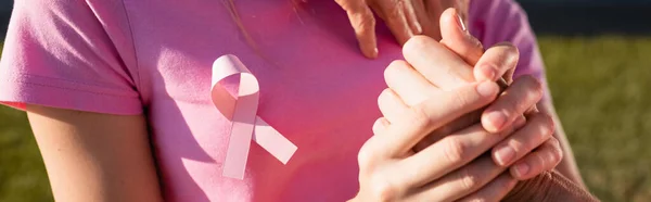 Colpo panoramico di donna con segno di consapevolezza del cancro al seno tenendosi per mano — Foto stock