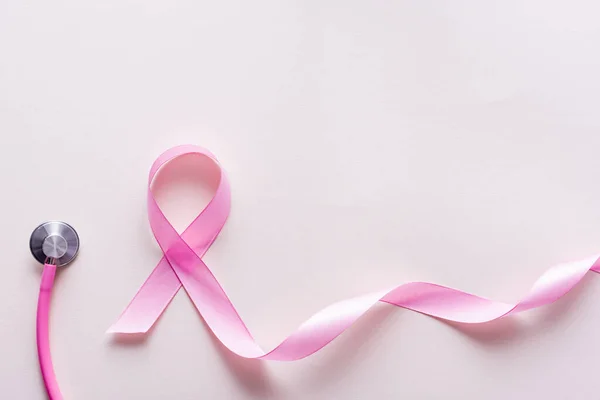 Close up view of pink ribbon near stethoscope isolated on white — Stock Photo