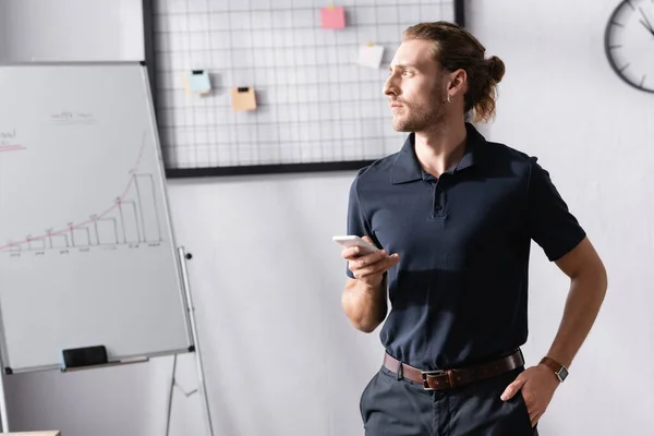 Empresário confiante com a mão no bolso olhando para longe enquanto estava perto flipchart no escritório — Fotografia de Stock