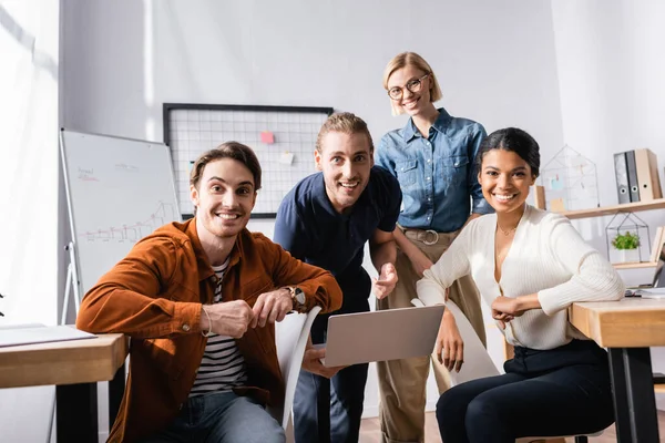 Multicultural, cheerful businesspeople looking at camera in office — Stock Photo