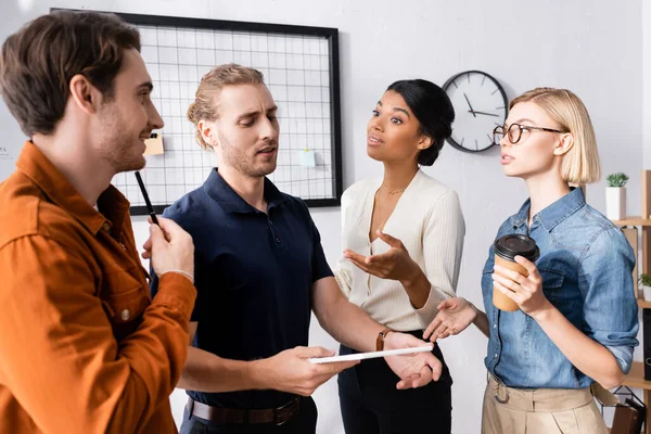 African american businesswoman pointing with hand while talking with multiethnic colleagues — Stock Photo