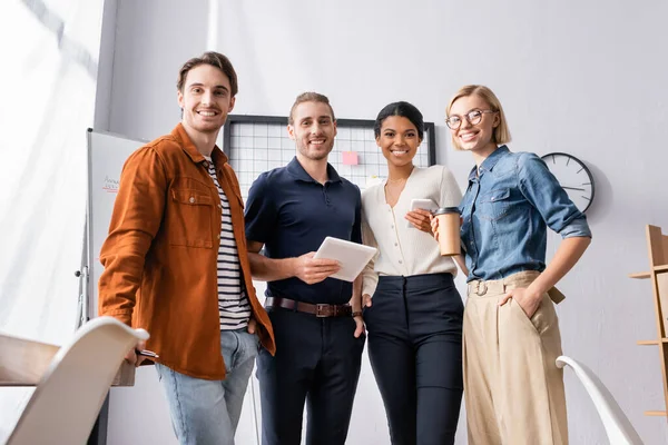 Happy, young multicultural businesspeople looking at camera in office — Stock Photo