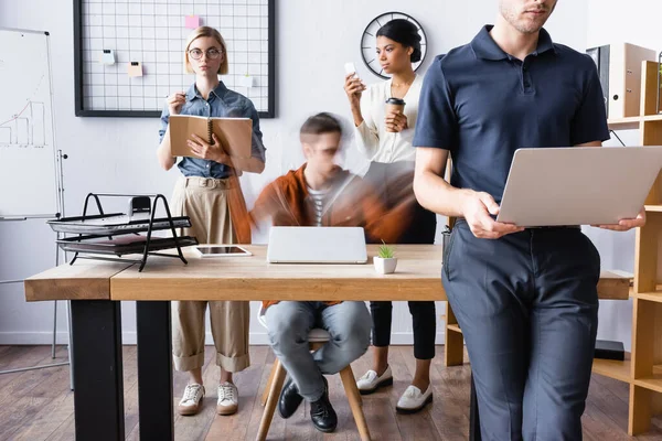 Young multiethnic businesspeople working with gadgets in open space office together, motion blur — Stock Photo