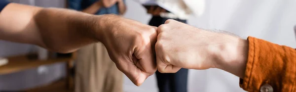 Partial view of businessmen doing fist bump near colleagues on blurred background, banner — Stock Photo