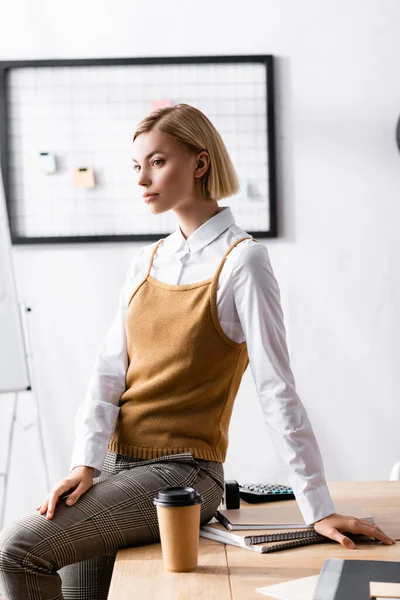 Nachdenkliche Geschäftsfrau sitzt am Schreibtisch neben Einwegbecher — Stockfoto