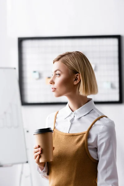 Pensive, blonde manager looking away while holding coffee to go — Stock Photo