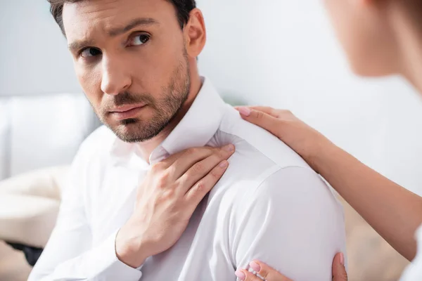 Uomo barbuto con spalla dolorosa guardando la donna in primo piano sfocato — Foto stock