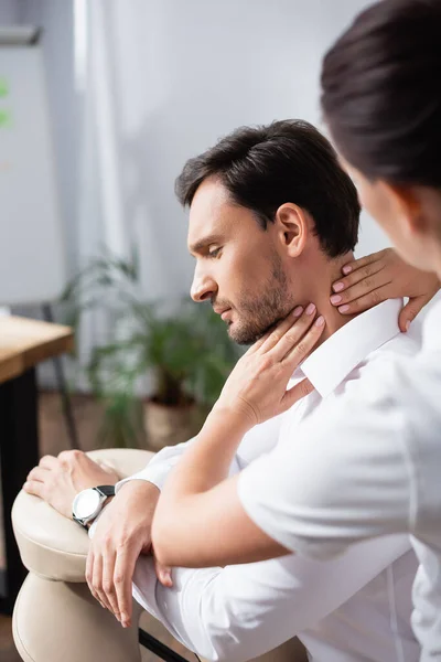 Massagem massagista pescoço de empresário sentado na cadeira de massagem no escritório em primeiro plano borrado — Fotografia de Stock