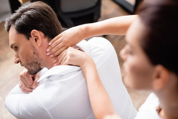 Vue aérienne de la masseuse massant le cou du client au bureau au premier plan flou — Photo de stock