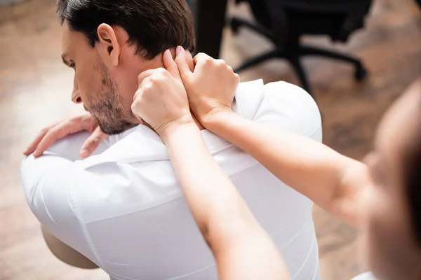 Massagista com as mãos estendidas massagear pescoço de homem de negócios em primeiro plano desfocado — Fotografia de Stock