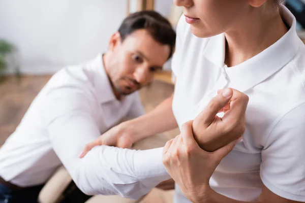 Masseuse doing arm massage for businessman on blurred background — Stock Photo