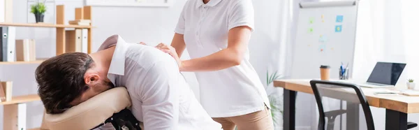 Masajista femenina masajeando espalda de hombre de negocios sentado en silla de masaje en la oficina, pancarta - foto de stock