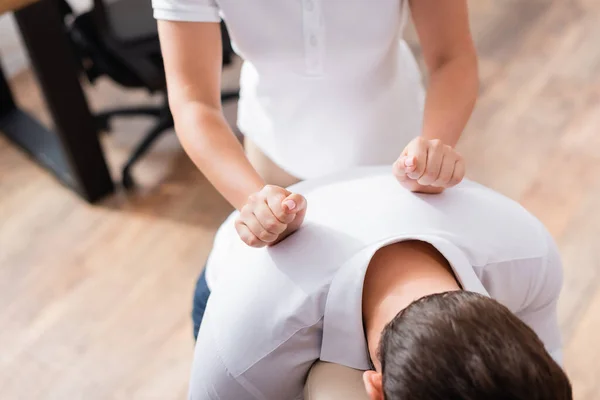 Ausgeschnittene Ansicht der Masseurin bei Rückenmassage für Klient im Büro auf verschwommenem Hintergrund — Stockfoto