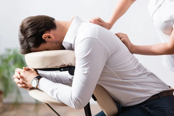 Side view of masseuse doing back massage for client on blurred background — Stock Photo