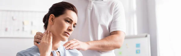 Massage therapist massaging hurting neck of female client with blurred office on background, banner — Stock Photo