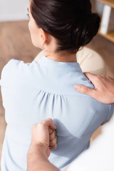 Close-up vista de massagista fazendo massagem sentada de empresária de volta no fundo borrado — Fotografia de Stock